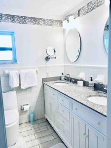 een badkamer met 2 wastafels, een toilet en een spiegel bij Island Vibes Beach House & 10 min walk to beach in Fort Pierce