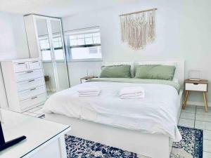 a white bedroom with a large bed with two towels on it at Island Vibes Beach House & 10 min walk to beach in Fort Pierce +52 photos