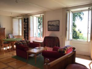 uma sala de estar com sofás, uma mesa e janelas em B&B Château de Denens 