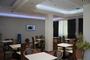 uma sala de jantar com mesas e cadeiras brancas em Hotel Mondo em Gjirokastër