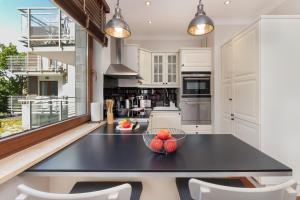a kitchen with a black table and white cabinets at Seaside Sopot Apartment with Parking and Gym by Renters in Sopot