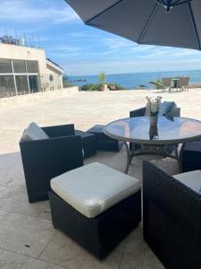 a patio with a table and chairs and an umbrella at Portelet Bay in St Brelade