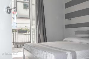a white bedroom with a bed and a balcony at L'Approdo Dell'Ammiraglio in La Spezia