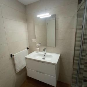 uma casa de banho branca com um lavatório e um espelho em Apartamento cerca de Granada em Cenes de la Vega