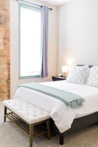 um quarto com uma cama grande e um banco em The Reserve - Heart of OTR 2 Bed Suite w/Views em Cincinnati