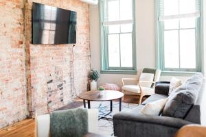 a living room with two couches and a brick wall at The Reserve - Heart of OTR 2 Bed Suite w/Views in Cincinnati