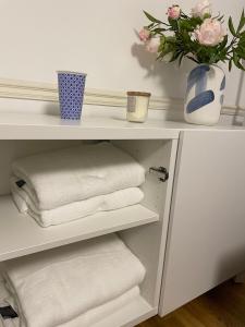 a white shelf with towels and a vase of flowers at Oxford City Centre Apartment with parking in Oxford