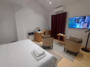 - une chambre avec un lit, deux chaises et une télévision dans l'établissement Balkanska Four Seasons Suites, à Belgrade