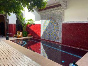 uma piscina num quarto com azulejos vermelhos e azuis em Riad La Perle Rouge em Marrakech