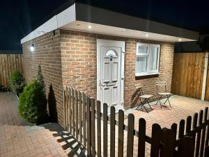 a small brick house with a white door and a bench at Modern Luxury Private Detached 1 Double Bedroom Studio Apartment - Super Fast Wifi in Luton
