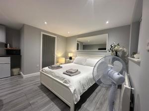 a bedroom with a white bed and a fan at Modern Luxury Private Detached 1 Double Bedroom Studio Apartment - Super Fast Wifi in Luton