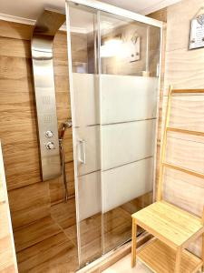 a shower with a glass door and a wooden chair at Cozy Apartment with parking near the city center in Athens