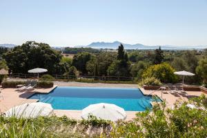 - une piscine avec deux parasols et des chaises dans l'établissement Hotel Llenaire, à Port de Pollença