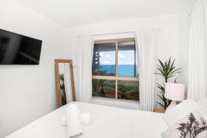 a bedroom with a white bed and a window at Beach View Mollymook in Mollymook +9 photos