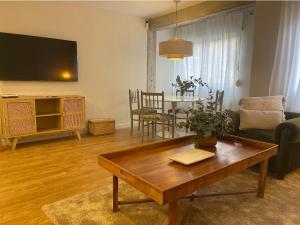 sala de estar con mesa de madera y sala de estar con TV. en APARTAMENTO 4 PAX RECIÉN REFORMADO EN EL CENTRO DE SANTANDER, en Santander