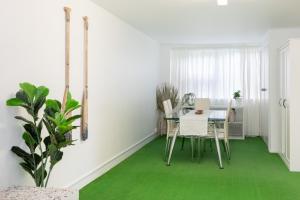 a dining room with green flooring and a table and chairs at Beach View Mollymook in Mollymook
