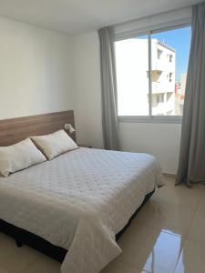 ein Schlafzimmer mit einem Bett und einem großen Fenster in der Unterkunft Dptos Corrientes con cochera in Corrientes
