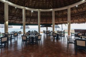 un restaurante en la playa con mesas y sillas en Hotel Cayman Suites, en Monterrico