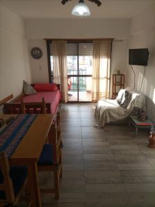a room with two beds and a table and a room with a window at Dpto AR in San Clemente del Tuyú