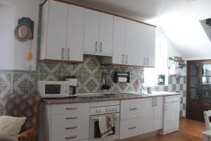 a kitchen with white cabinets and a microwave at Casa Rural El Nini in La Coronada