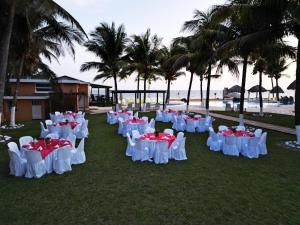 una fila de mesas y sillas en la hierba con palmeras en Hotel Cayman Suites, en Monterrico
