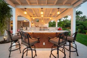 a patio with four chairs and a bar on a house at Sugar Hill - Fiddlesticks villa in Saint James