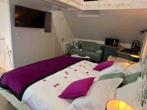 een slaapkamer met een groot bed met paarse kussens bij Le Cocon des Remparts-Logis Élégant à Pierrefonds in Pierrefonds