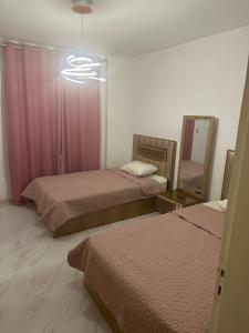 a bedroom with two beds and a mirror and pink curtains at شقة فندقية جديدة في مدينتي in Cairo