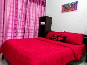 ein rotes Bett in einem Schlafzimmer mit rosa Vorhängen in der Unterkunft Kuantan Homestay Best Facility Wifi BBQ Viu in Kuantan