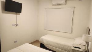 a room with two beds and a flat screen tv at DEPARTAMENTOS CIELO DE CAFAYATE in Cafayate