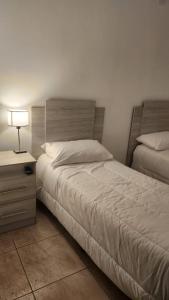 1 dormitorio con 2 camas y mesita de noche con lámpara en DEPARTAMENTOS CIELO DE CAFAYATE en Cafayate