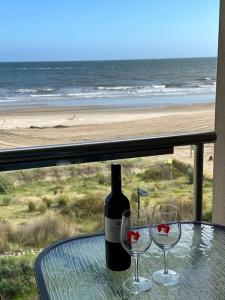 a bottle of wine sitting on a table with two glasses at Absolute Beachfront at the Pier Glenelg in Adelaide