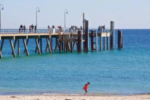 a person walking on the beach near a pier at Absolute Beachfront at the Pier Glenelg in Adelaide
