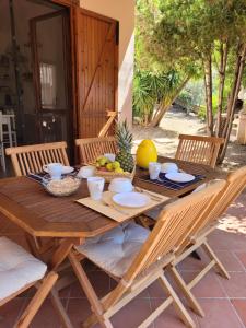 a wooden table with plates and bowls of fruit on it at Casa del Mare in Villasimius