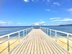 un paseo marítimo de madera que conduce al océano en una playa en Pension Coco, en Ishigaki Island