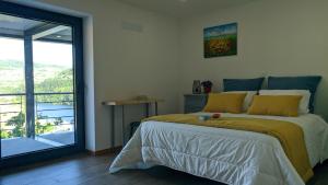 a bedroom with a bed with yellow pillows and a window at Casa do Geraço - Douro Guest House in Várzea do Douro
