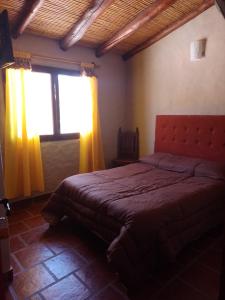 a bedroom with a bed and a window with yellow curtains at Hotel La Herencia in Tilcara