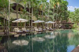 basen z leżakami i parasolami obok budynku w obiekcie Pavillon d'Orient Boutique Hotel w Siem Reap