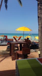 a man sitting at a table under an umbrella on the beach at Arisara place in Koh Samui 