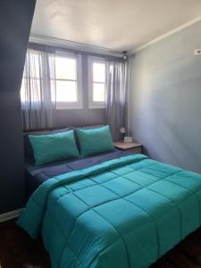 a bedroom with a bed with blue sheets and windows at Casa Ribera Hotel Providencia in Santiago