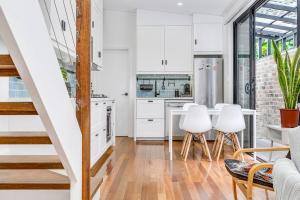 a kitchen with white cabinets and a table and chairs at A Charming Sunny Terrace in the Heart of Newtown in Sydney