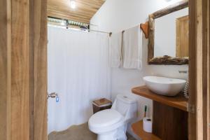 y baño con aseo blanco y lavamanos. en Finca Amistad Cacao Lodge, en Bijagua