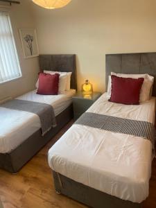 two beds with red pillows in a bedroom at Home away from Home in Cross Gates