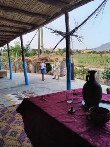 uma mesa com um vaso sobre uma toalha de mesa roxa em auberge yeswal aoulad yaakoube 