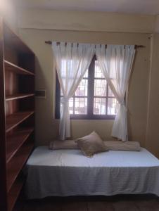a bed in a room with a window with white curtains at Scenario Yguazu in Puerto Iguazú