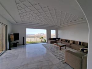 Villa avec vue panoramique في طنجة: غرفة معيشة مع أريكة وتلفزيون