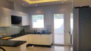 a kitchen with white cabinets and two large windows at Villa avec vue panoramique in Tangier