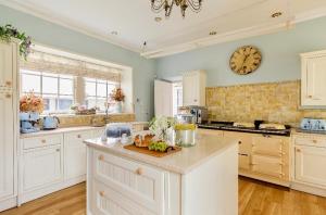 a kitchen with white cabinets and a clock on the wall at Private room & bathroom in Manor House in Maybole