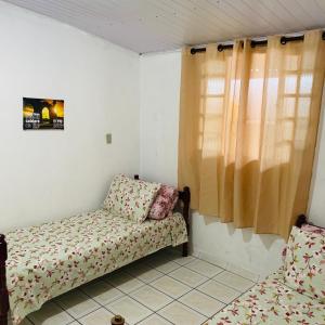 Cette petite chambre comprend un canapé et une fenêtre. dans l'établissement Mãezinha do céu, à Aparecida