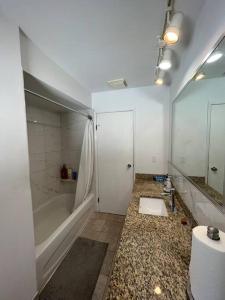 a white bathroom with a tub and a sink at Two Bedrooms Marpole Vancouver in Vancouver